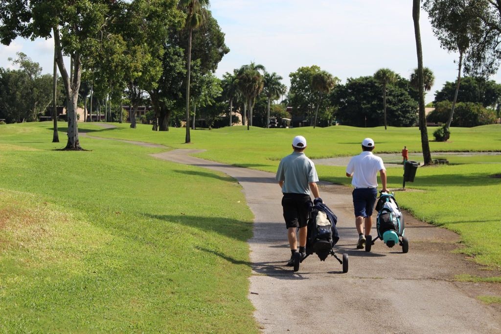 Golfers pulling club bag on golf course path